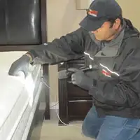 Bed bug inspection technician checking a mattress and bed frame for signs of infestation in El Paso, TX