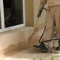 General pest control technician spraying exterior perimeter around a home in El Paso, TX