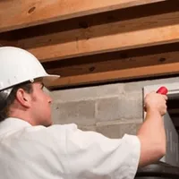 Termite inspection technician checking a basement wall and framing for termite activity in El Paso, TX