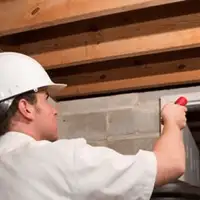 Termite inspection technician checking a basement wall and framing for termite activity in El Paso, TX